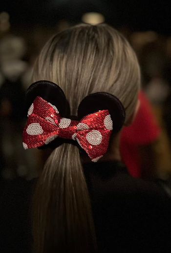 A person wearing a sequined Minnie Mouse bow headband, viewed from behind