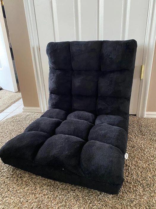 A soft, tufted floor chair positioned near a door in a warm, inviting room