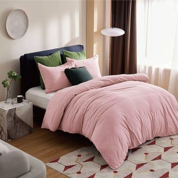 A pink duvet set draped over a bed.