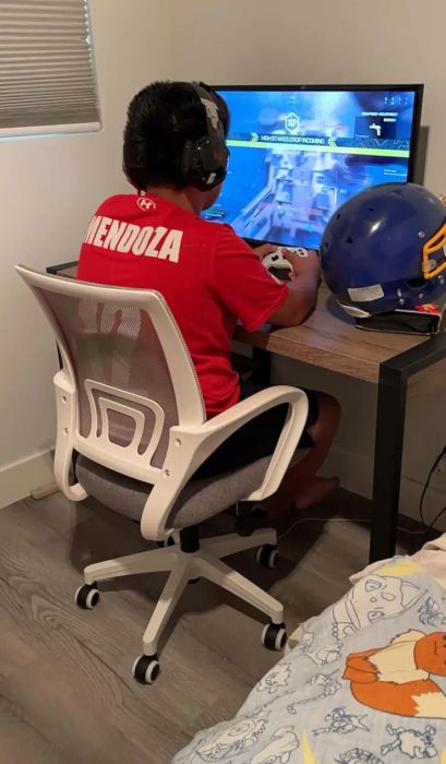 A person enjoying a video game at a desk, wearing a red shirt