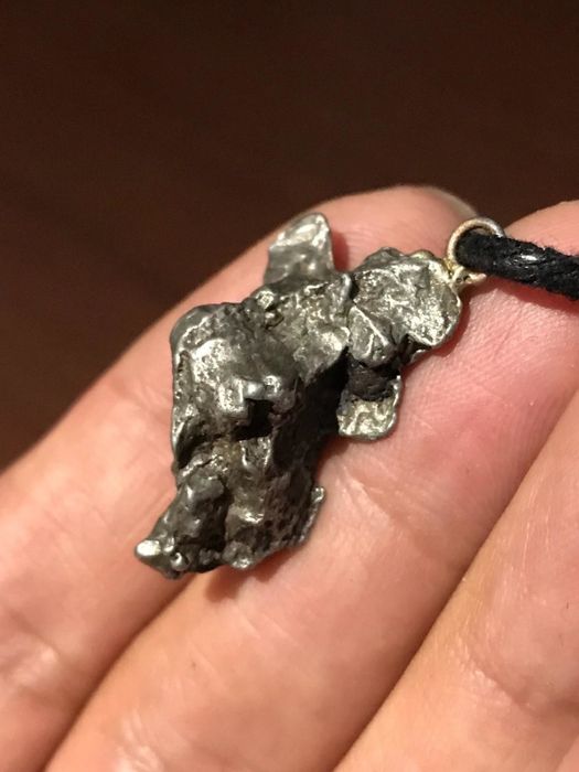 reviewer photo showing a small piece of meteorite encased in a pendant