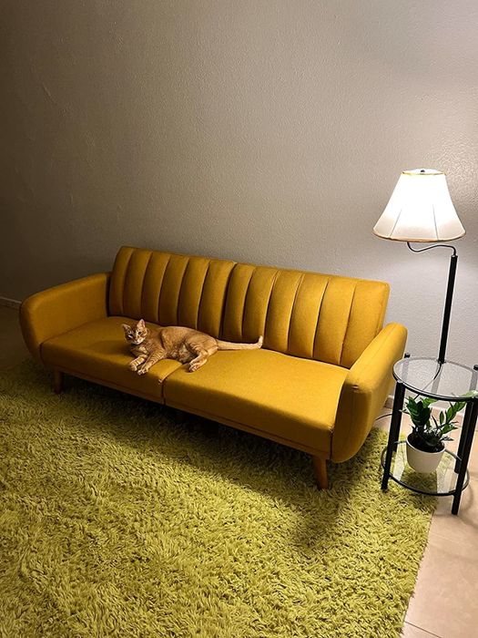 A reviewer's photo of the mustard yellow futon in its cozy setting