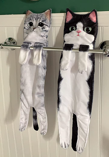 Gray and black cat figurines perched on a metal shelf in a bathroom, adding character to the space.