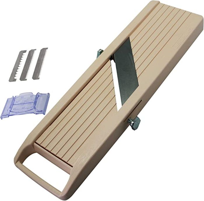 A photo showcasing a mandoline slicer along with its accessories, such as a guard and various blades