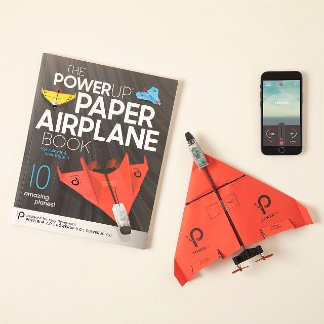 A red paper airplane alongside a template book and a smartphone, ready for takeoff.