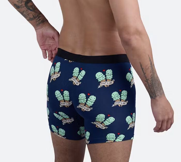 A man shows off a pair of boxers with a cactus motif and the phrase 
