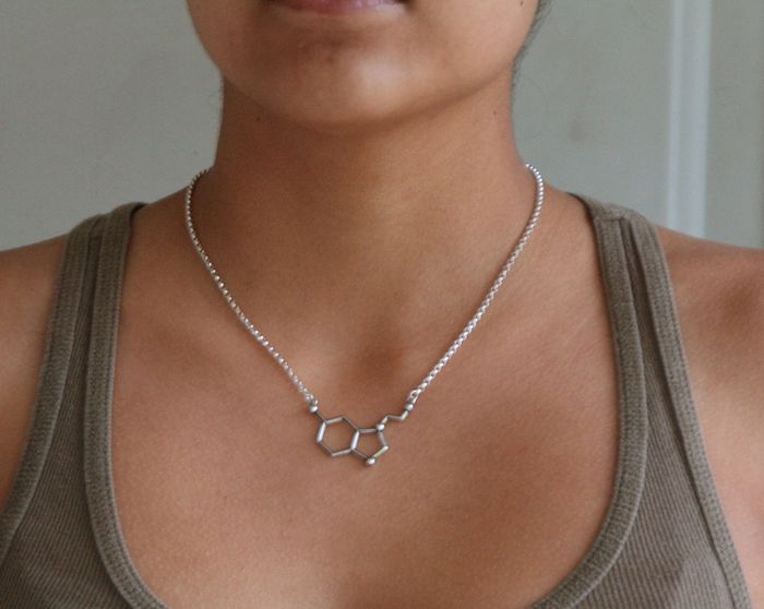 A woman sporting a tank top, accessorized with a necklace that showcases a molecular structure pendant.