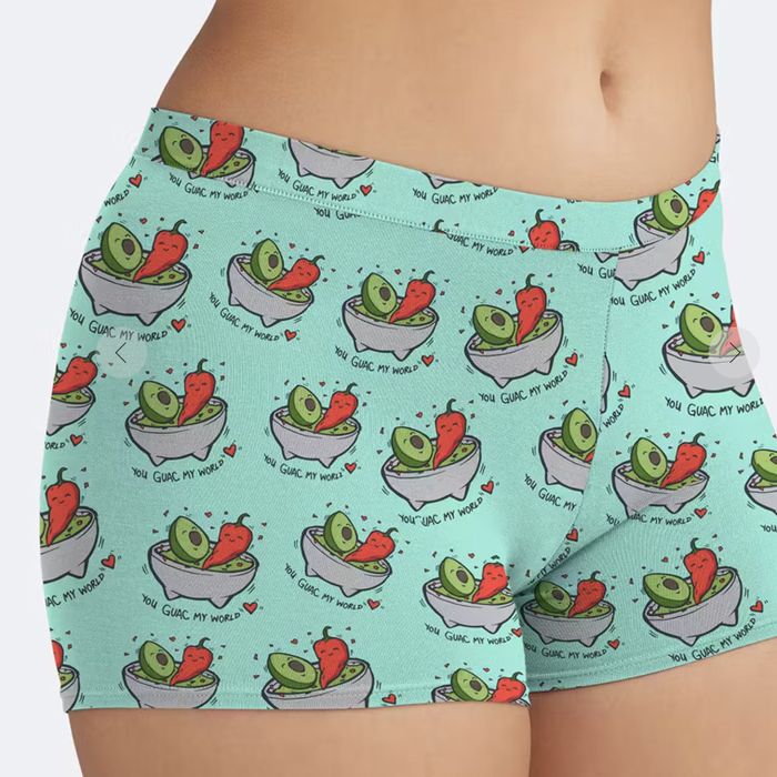 Woman modeling boyshorts with a fun avocado and taco design, featuring the playful text 