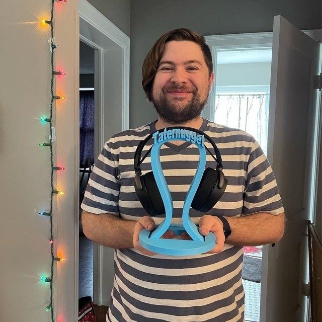 A reviewer proudly showing off a blue headphone stand with the name 