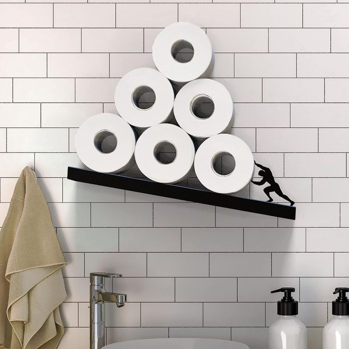 Close-up of a shelf with the silhouette of a person holding up the toilet paper