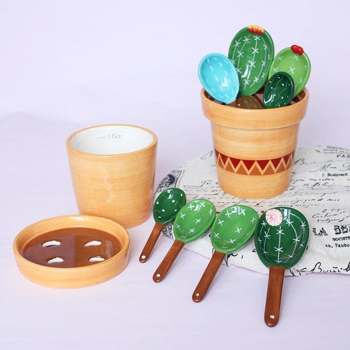 Four cactus-designed measuring spoons with a potted cup holder arranged on a table