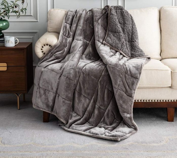 A plush throw blanket draped over a sofa in a cozy living room, with a caption promoting comfort above it.
