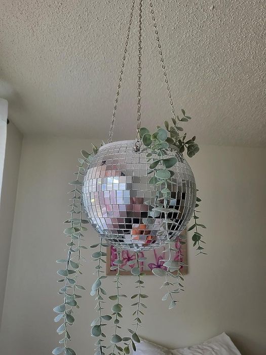 A silver disco ball planter with a plant hanging from the ceiling