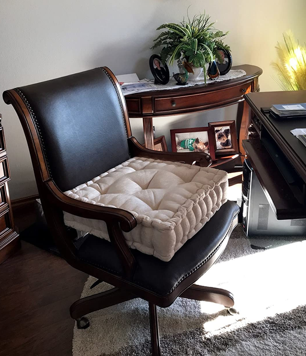 A photo from the reviewer showing the beige pillow resting on a desk chair