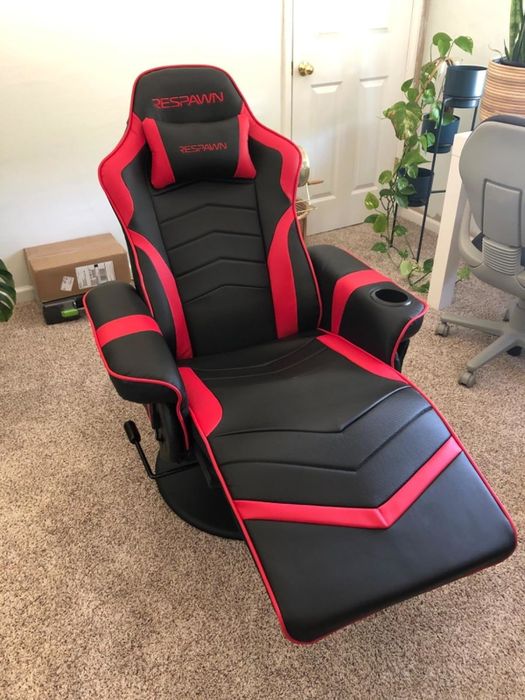 A RESPAWN gaming chair in a home office setup, featuring a footrest, armrests, and a headrest with the 'RESPAWN' logo clearly visible.