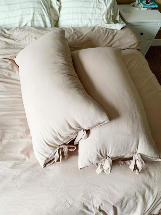 Two long rectangular pillows in tan pillowcases.