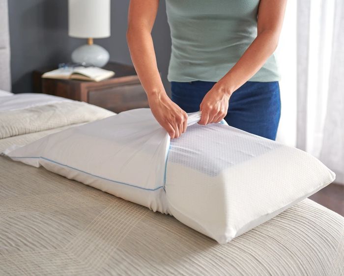 A model demonstrating how the removable and washable knit cover easily comes off the pillow.
