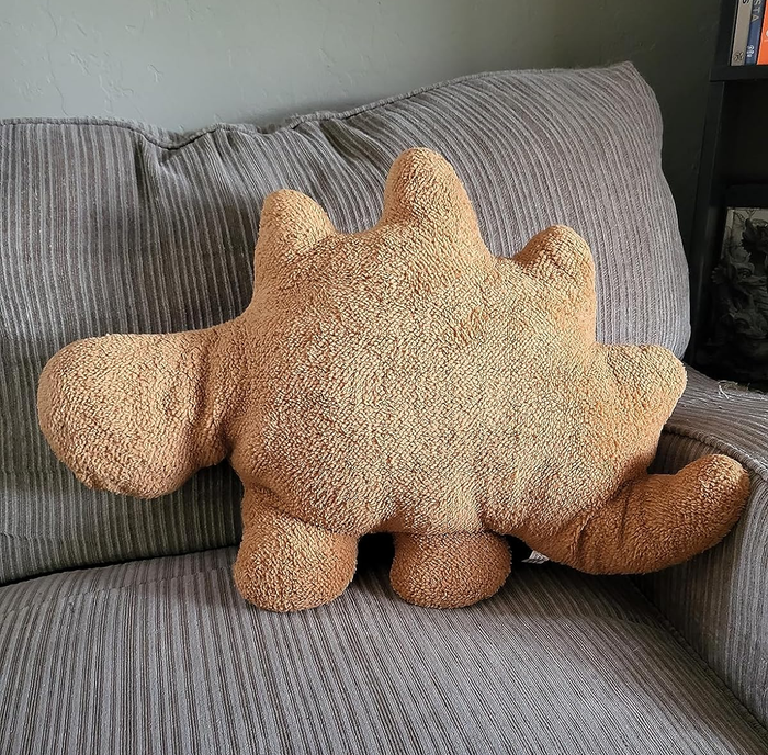 A dino nugget pillow resting on the reviewer's couch
