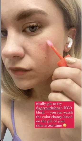 An editor applying the blush, which transforms from clear to a pink shade on their cheeks.