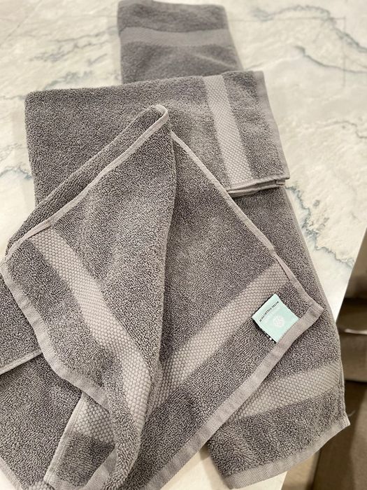 Reviewer image showing four gray cotton towels, both folded and unfolded, neatly arranged on a counter