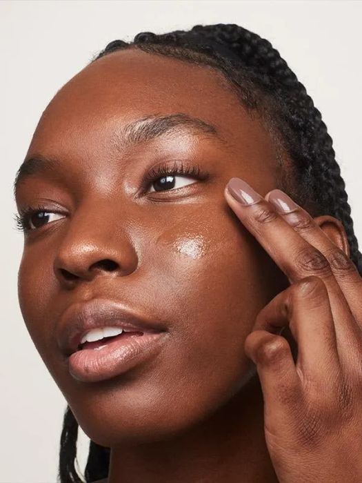A dark-skinned model applying the product, showcasing how seamlessly it blends into the skin.