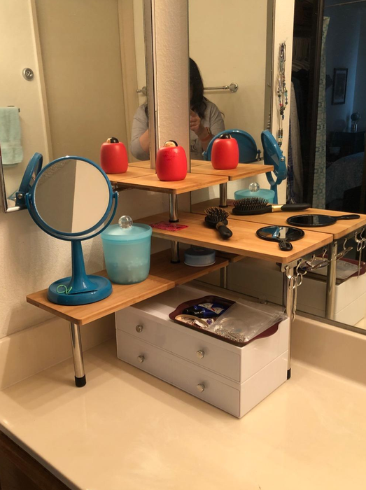 A set of corner shelves in the reviewer’s bathroom, neatly arranged with products