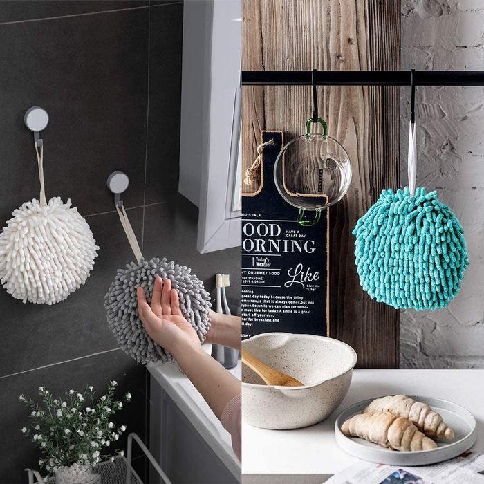 Model showcasing a gray, ball-shaped hand towel hanging on the wall next to a white towel, with a blue towel on a black hook in the kitchen