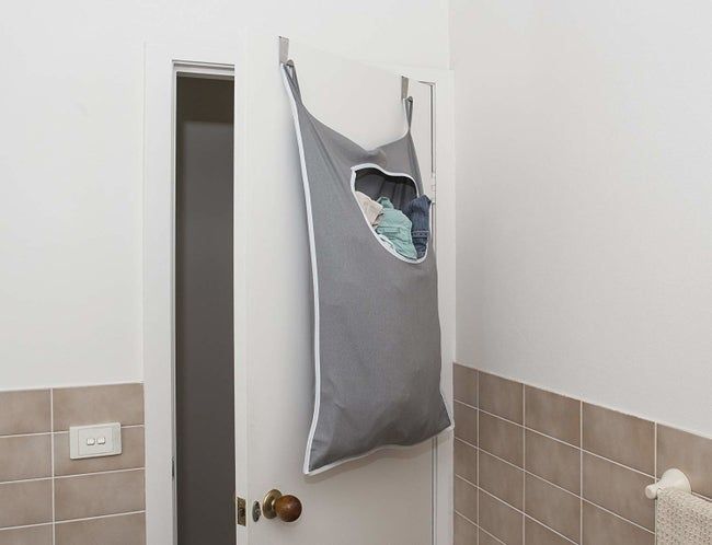 The back of a bathroom door with a small, hanging laundry hamper attached