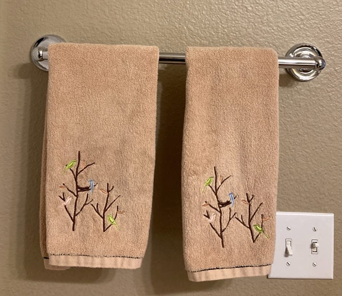 A reviewer image featuring two brown hand towels adorned with embroidered birds perched on trees