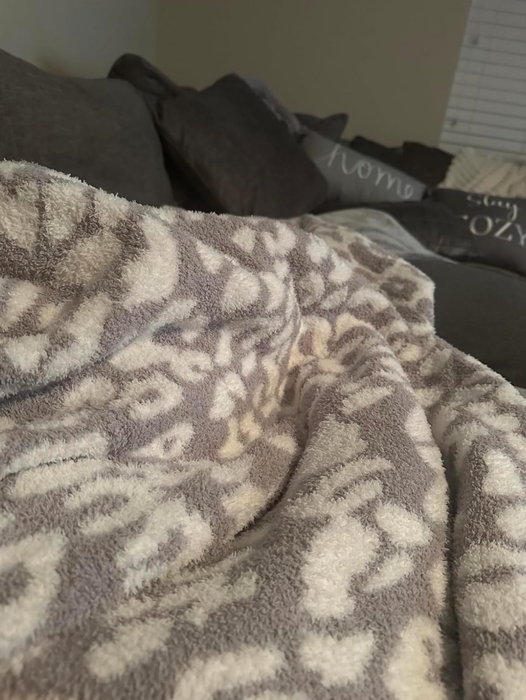A soft, patterned blanket draped over a plush sofa, with pillows nestled in a warm and inviting living room space.