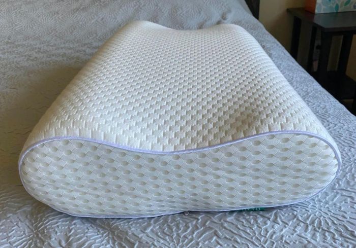 Ergonomically designed memory foam pillow resting on a bed with textured bedding, offering optimal neck support for a restful sleep.