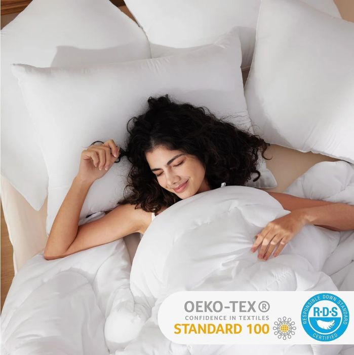 A woman enjoys a restful night on a bed with several pillows and a cozy comforter, highlighting Oeko-Tex and RDS certifications for the textiles used.