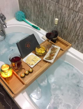 A reviewer's photo of the caddy holding wine, a candle, and snacks.