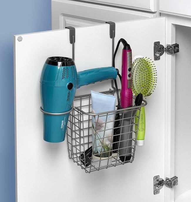 A bathroom cabinet with an over-the-door basket organizer filled with various hair tools.