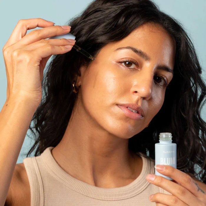 A model gently applying the acne oil to their cheek, targeting problem areas.