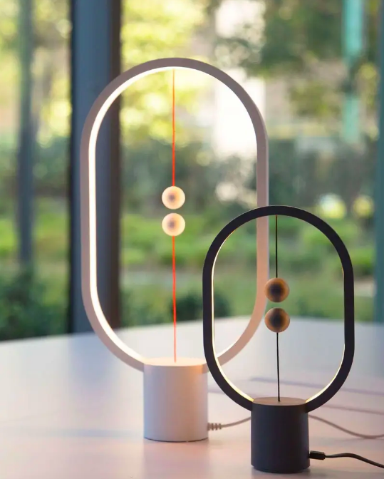 Oval light rings with a central base and two magnetic spheres attached to strings at the top and bottom of the light