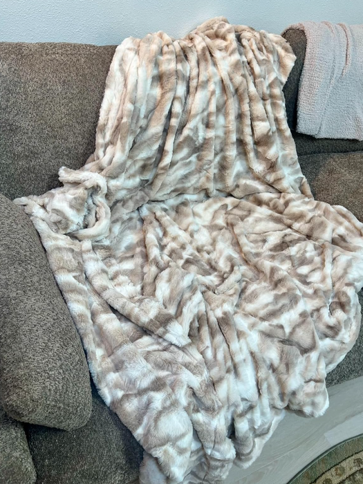 A faux fur blanket draped over a sofa, creating a soft and inviting look.
