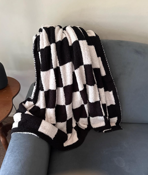 A checkered blanket draped over a gray couch, with a small wooden table positioned nearby.
