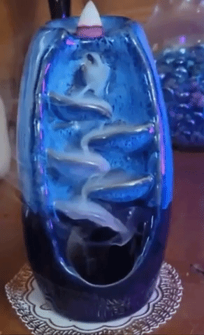 A gif showing a blue incense burner with smoke cascading down like a waterfall