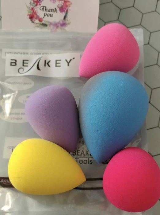 Five teardrop-shaped makeup sponges in varying sizes and colors.