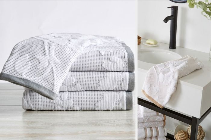 Gray and white floral towels stacked neatly on a table, with a yellow and white towel draped over a pristine white sink