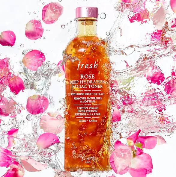 A bottle of Fresh Rose Deep Hydration Facial Toner, featuring rose petals and a crystal-clear formula, set against a background of pink roses.