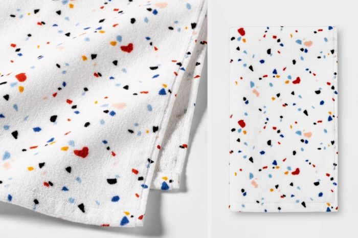 A red, blue, black, and yellow speckled towel neatly folded against a white background
