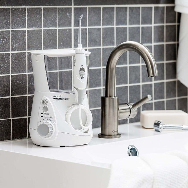 A water flosser charging on its stand on a bathroom sink