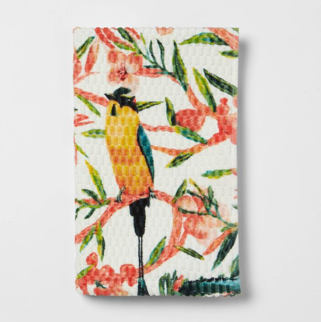 A towel with yellow and blue birds perched on pink and green branches, set against a white background