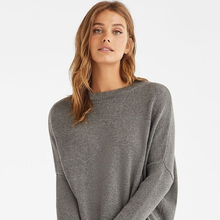 A model wearing the long sweater as a crewneck in grey.