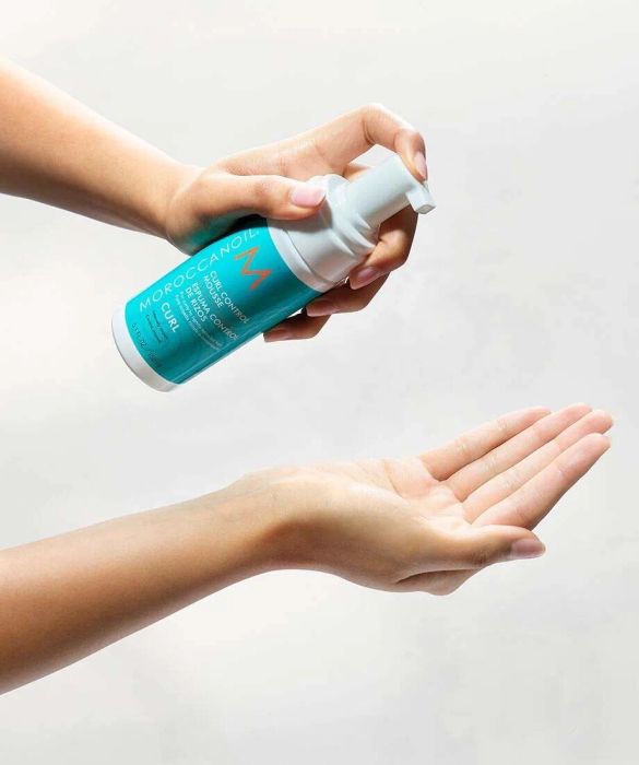 A hand holding a blue plastic bottle with a white cap.