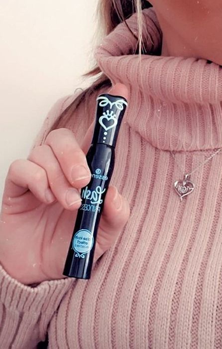 A reviewer holding the sleek black mascara tube