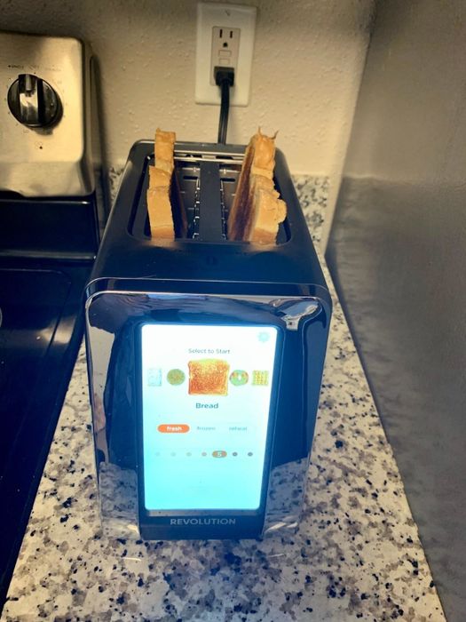 A top front view of the high-tech screen on the toaster displaying the toasting level, with two perfectly toasted slices of bread inside the slots