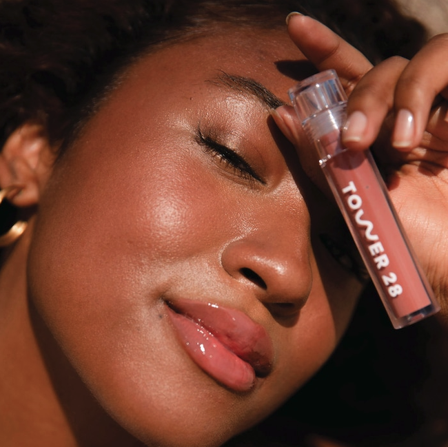 A model poses with the gloss tube, wearing the pink/brownish shade